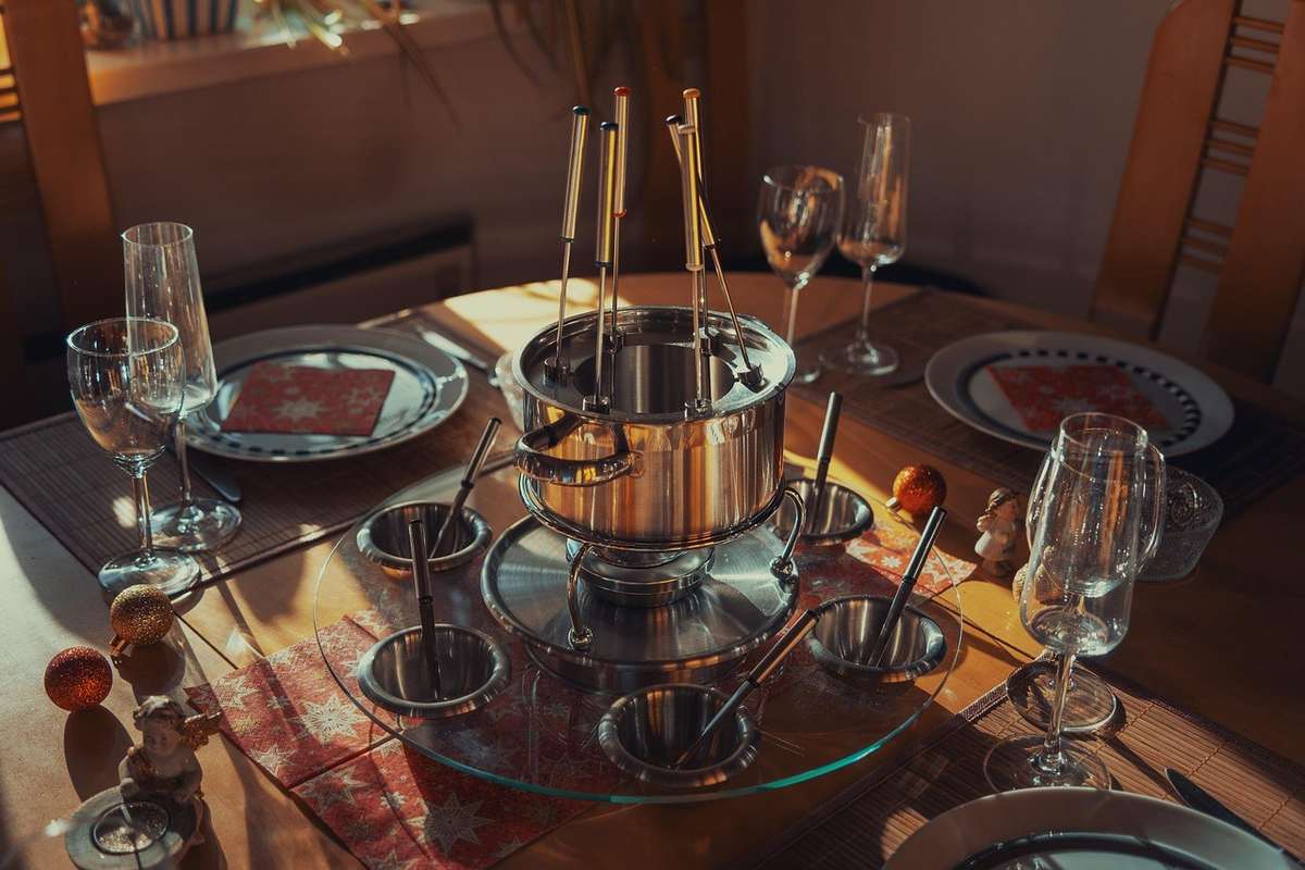Table préparée pour un repas avec plat, verres et bouilloire en centre