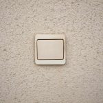 Un interrupteur lumineux blanc sur un mur texturé hors tension