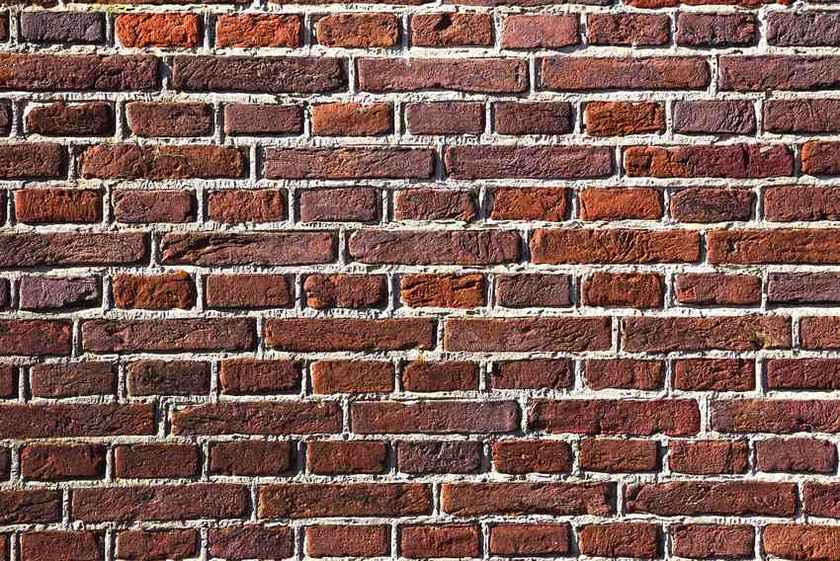 Mur construit avec des briques de différentes teintes de rouge et marron